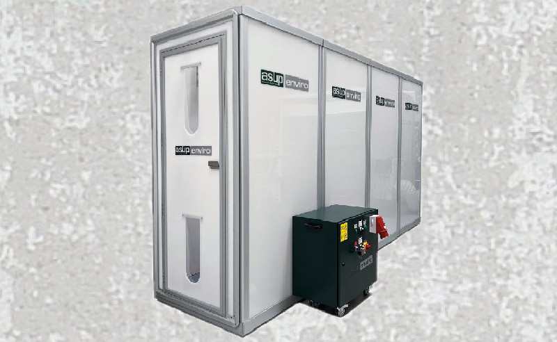 Das Bild zeigt eine containerartige Struktur mit einer transparenten Front und dem Logo "asup enviro". Neben der Struktur befindet sich ein dunkler, rechteckiger Kasten mit Steuerungselementen. Die Gesamtgestaltung vermittelt einen technischen Eindruck, möglicherweise für Anwendungsbereiche im Umweltschutz oder der Abfallentsorgung.